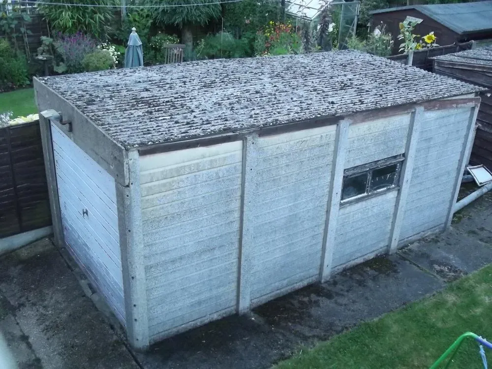 Old garage with a corrugated asbestos cement roof awaiting safe removal.