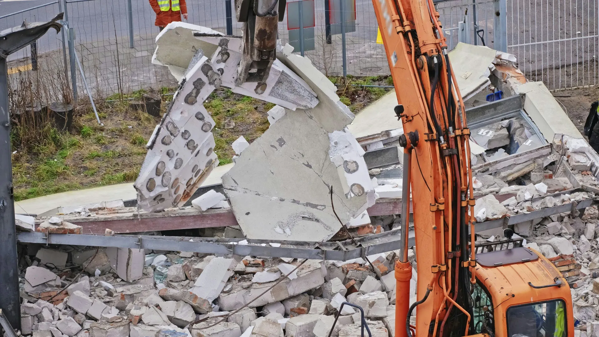 An excavator demolishing a building, indicating large-scale asbestos removal for commercial or industrial properties.
